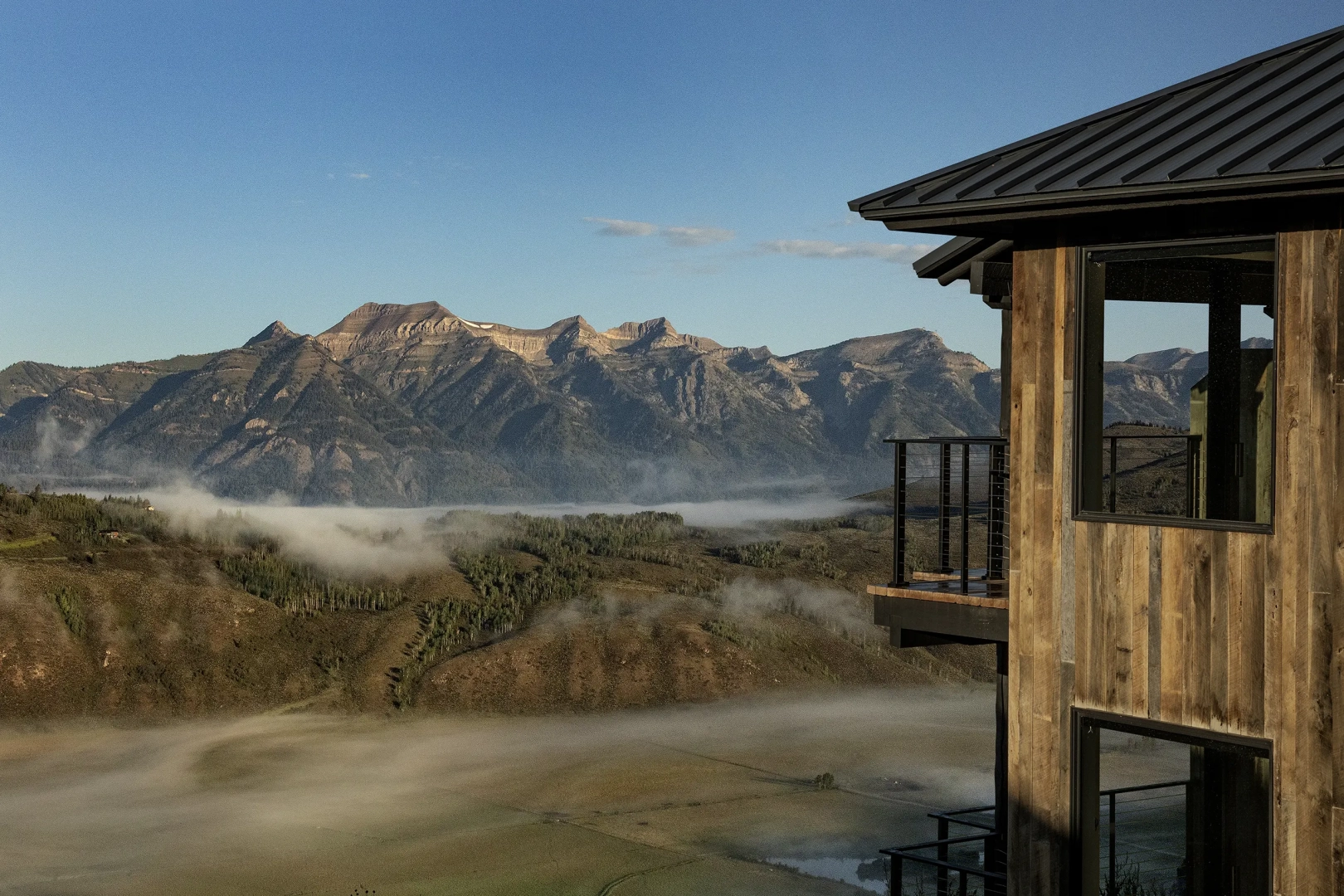 Exterior view of the Vista Suite with wooden accents, large windows, and a balcony overlooking scenic natural surroundings.
